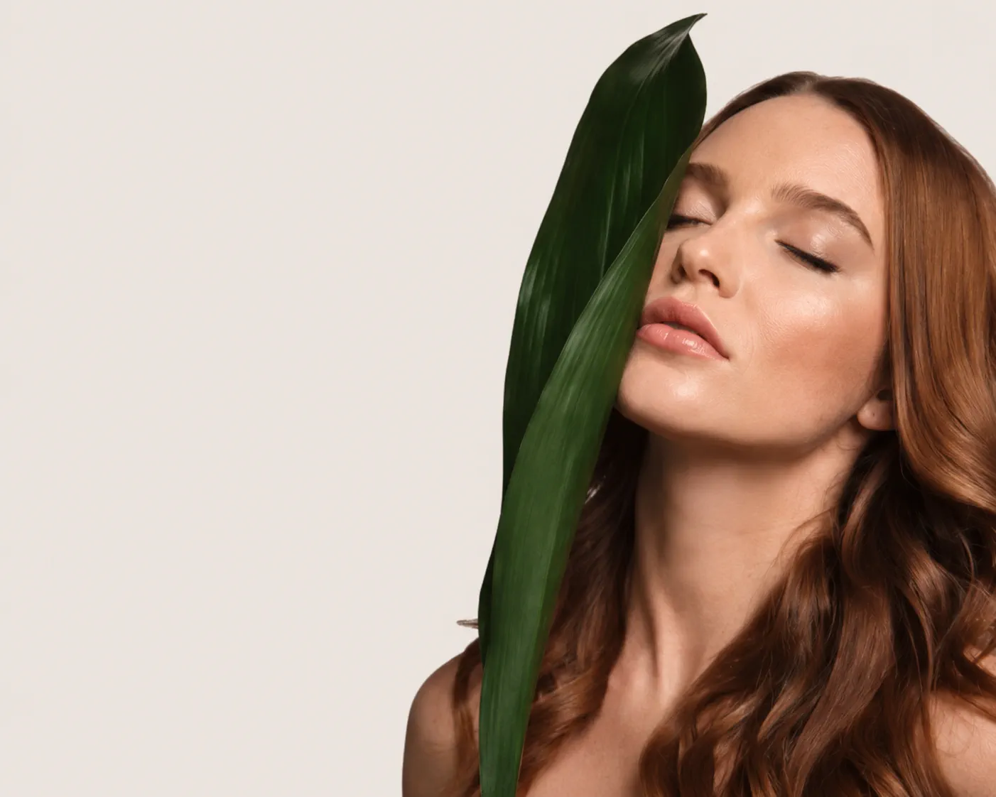 Model with glossy hair holding a leaf